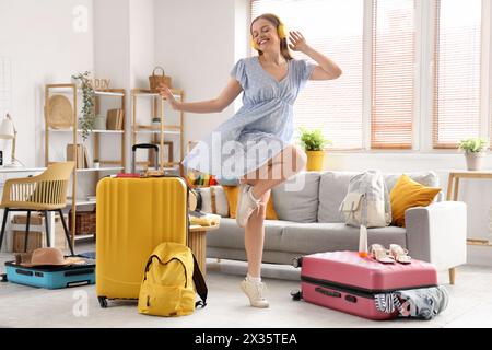 Jeune femme enceinte dans des écouteurs avec des sacs prêts pour des vacances à la maison Banque D'Images