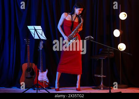 Belle femme jouant du saxophone sur scène Banque D'Images