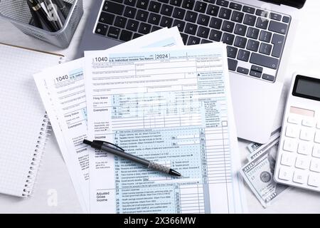 Formulaires fiscaux, argent, papeterie, ordinateur portable et calculatrice sur table gris clair, pose à plat Banque D'Images