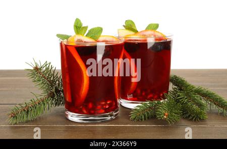 Boisson aromatique de Sangria de Noël dans des verres et des branches de sapin sur une table en bois sur fond blanc Banque D'Images