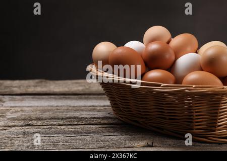 Oeufs de poule frais dans un panier en osier sur une table en bois. Espace pour le texte Banque D'Images