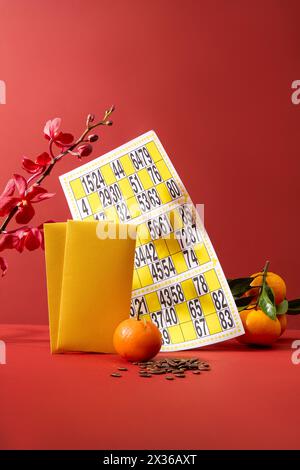 Une carte de bingo décorée de mandarines et d'enveloppes jaunes. Un tas de graines de melon affichées. Le nouvel an lunaire est une période pour les réunions de famille Banque D'Images