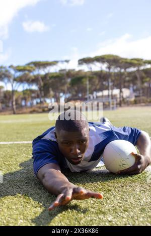 Un jeune joueur de rugby afro-américain marquant un essai sur un terrain en herbe Banque D'Images