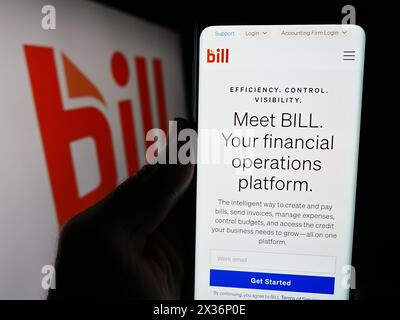 Personne tenant le téléphone portable avec la page Web de la société américaine de logiciels financiers BILL Holdings Inc devant le logo. Concentrez-vous sur le centre de l'écran du téléphone. Banque D'Images