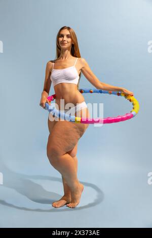 Motivation à être belle et en bonne santé. Jeune fille mince avec le corps de la femme grande taille faisant des exercices avec cerceau. Création conceptuelle. Banque D'Images