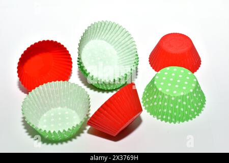 Les moules en papier pour la cuisson des cupcakes reposent chaotiquement sur un fond blanc. Banque D'Images