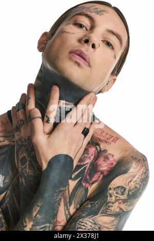 Un jeune homme élégant avec un éventail de tatouages complexes ornant son corps, mettant en valeur son sens unique de l'art et de l'expression de soi. Banque D'Images