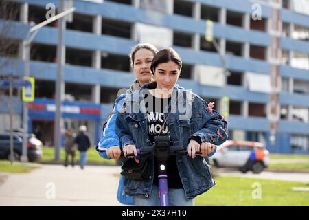 Deux filles chevauchant sur scooter électrique ensemble, loisirs dans la ville de printemps Banque D'Images