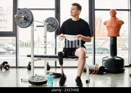 Un homme avec une jambe prothétique est assis sur un banc de gymnastique, profondément dans la pensée, alors qu'il prend une pause de sa routine d'entraînement. Banque D'Images