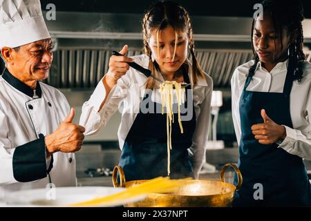 Chef instruit dans la cuisine. Les écolières font des nouilles japonaises. Enfants et professeur à poêle. Souriant Banque D'Images