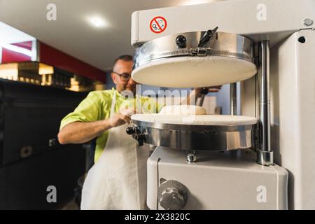 homme boulanger d'âge moyen préparant la pâte pour la pizza dans la cuisine. Photo de haute qualité Banque D'Images
