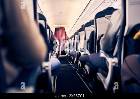 La cabine d'un avion commercial avec des rangées de sièges le long de l'allée. Lumière du matin dans la cabine de la compagnie aérienne. Classe économique. Photo de haute qualité Banque D'Images