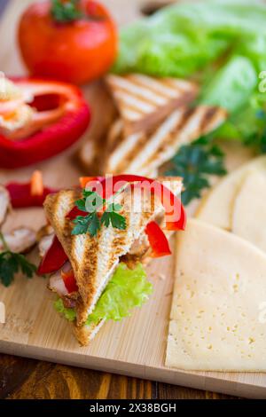 toast frit avec poulet, salade, légumes verts sur une table en bois. Banque D'Images