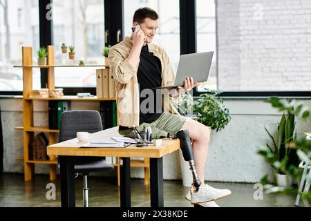 Un bel homme d'affaires avec une jambe prothétique travaille à une table en utilisant un ordinateur portable. Banque D'Images