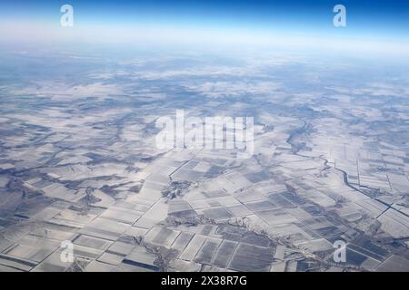 Plaines enneigées et rivières en hiver, vue depuis la fenêtre de l'avion volant Banque D'Images