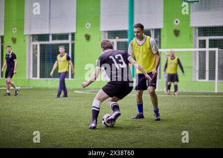 un juge, quatre joueurs. Épisode dans le jeu de futsal entre les équipes sur le terrain intérieur. Banque D'Images