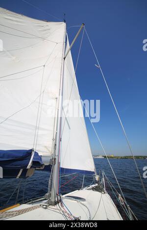 Grande voile de yacht blanc moderne naviguant sur la rivière à la journée ensoleillée d'été Banque D'Images