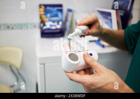 Mains de médecin avec modèle en plastique de mâchoire humaine et brosse à dents électrique. Banque D'Images