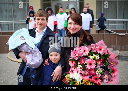 Homme avec nouveau-né, fille, femme avec des fleurs se tiennent près de la maternité, neuf personnes hors de portée Banque D'Images