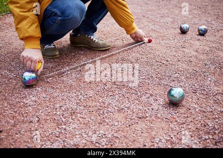 L'homme mesure la distance entre les balles pendant le jeu de pétanque. Banque D'Images