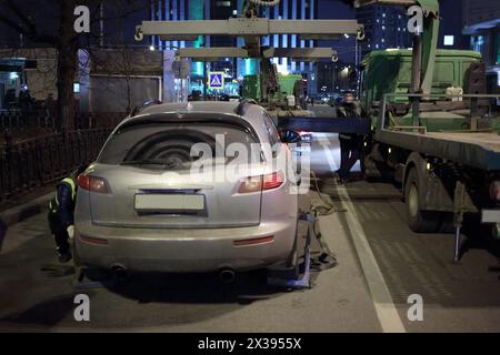 La dépanneuse se fait écraser une voiture grise sur la route. Banque D'Images