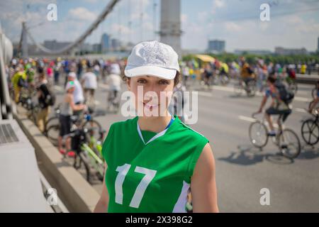 Femme heureuse en uniforme de sport vert se tient près du pont pendant la parade de vélo, dof peu profond Banque D'Images