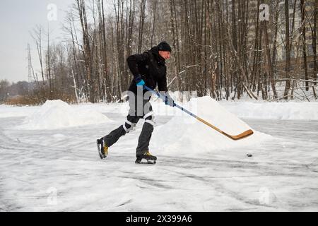 Joueur de hockey seul à la patinoire extérieure. Banque D'Images