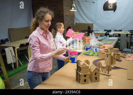 Une jeune femme et une petite fille peignent des maisons en carton. Banque D'Images