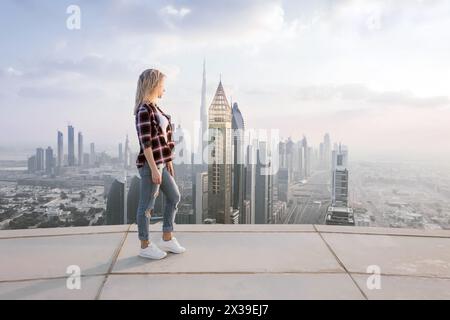 Femme se tient sur le toit d'un gratte-ciel à Dubaï lors d'une journée chaude, Émirats arabes Unis Banque D'Images
