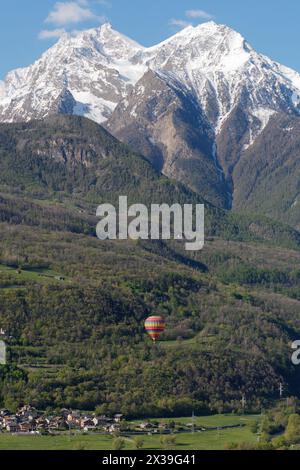 Montgolfière avec des alpes enneigées derrière près des villes de nus et Fenis dans la vallée d'Aoste, région Italie, 25 avril 2024 Banque D'Images