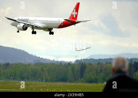 Helvetic Airlines Embraer E195-E2 ERJ 190-400 STD immatriculé HB-AZK atterrit à l'aéroport de Kloten, Zurich, tandis qu'un observateur l'observe avec un autre avion décoller d'une autre piste Copyright : xSergioxBrunettix Banque D'Images