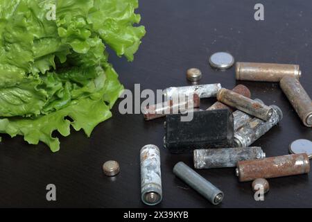 Piles usagées et laitue verte poussant dans un pot. Recyclage des piles usagées. Protection de l'environnement. Jour de la Terre. Banque D'Images