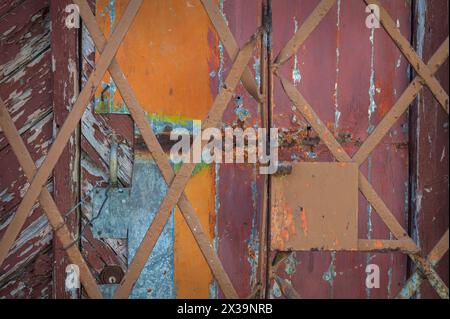 Une photo en gros plan d'une grille métallique et d'un mur en bois et d'une porte en bois gravement altérés avec de la peinture écaillée, dans les ruelles de Cienfuegos, Cuba Banque D'Images