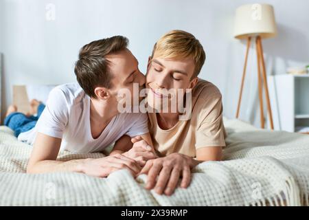 Deux hommes allongés sur un lit, partageant un baiser passionné. Banque D'Images