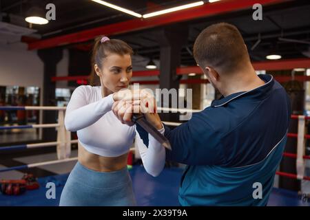 Femme exerçant avec un entraîneur d'arts martiaux pratiquant l'auto-défense à partir du couteau Banque D'Images