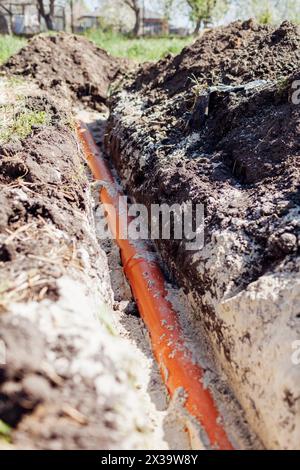 Tuyaux d'eaux usées assemblés dans une tranchée recouverte de sable. Maison de construction. Plomberie pendant la construction Banque D'Images