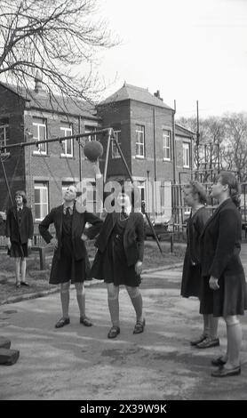 Années 1970, historique, écolières jouant au netball à l'extérieur dans le terrain de jeu de l'école, Angleterre, Royaume-Uni. Banque D'Images