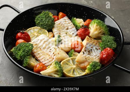 Morue savoureuse cuite avec des légumes dans une poêle à frire sur une table grise Banque D'Images