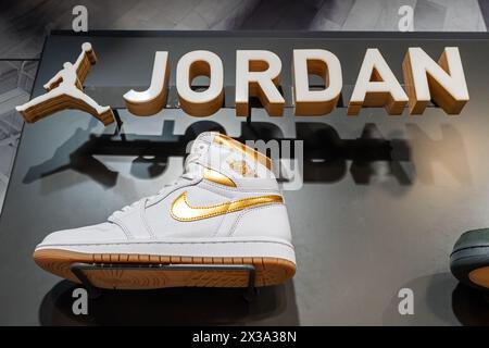 Jordan marque Jumping homme logo et baskets Nike Air Jordan 1 Retro High OG 'White and Gold' dans le magasin de la marque. Minsk, Biélorussie - 24 avril 2024 Banque D'Images