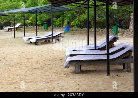 Zone de loisirs de plage sur la rive du lac. Des transats vides se tiennent sur le sable. La plage attend les touristes. Banque D'Images