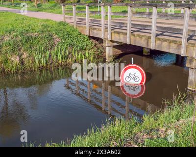 Panneau d'interdiction pour faire du vélo sous un pont dans un canal d'eau. Banque D'Images