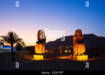 Les colosses de Memnon (statues colossales du pharaon Amenhotep III) au crépuscule sur la Cisjordanie de Louxor, en Égypte Banque D'Images