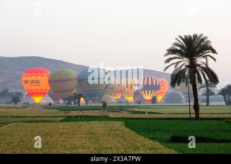 Montgolfières colorées décollant au lever du soleil de la Cisjordanie de Louxor, en Égypte Banque D'Images