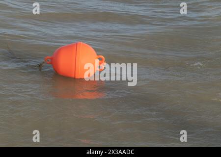 Une photo d'un bouillon en plastique orange flottant dans la mer Banque D'Images