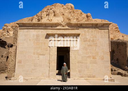 Un égyptien en tenue traditionnelle à l'entrée principale du temple de Hathor à Deir el-Medina sur la Cisjordanie de Louxor, en Égypte Banque D'Images