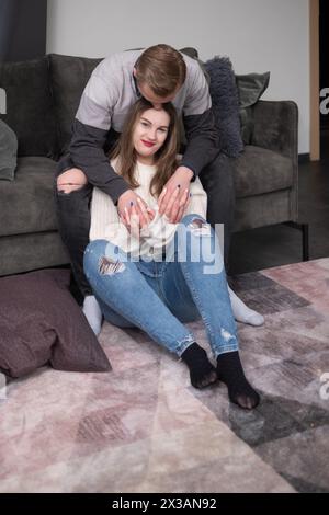 Un couple assis étroitement sur un canapé partage une étreinte réconfortante, leurs expressions de soin et de connexion célébrant l'amour et la compréhension, résonnance Banque D'Images