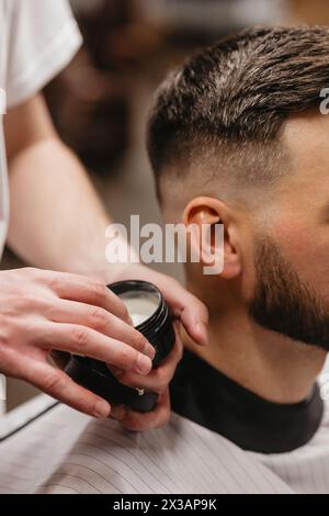 Un homme barbu est assis pour une coupe de cheveux dans un salon de coiffure Banque D'Images