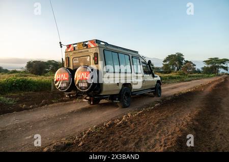 5 février 2024. Parc national d'amboseli, Kenya. Touristes dans un safari hors route voiture avec un toit ouvert prenant des photos d'animaux sauvages. parc national en i Banque D'Images