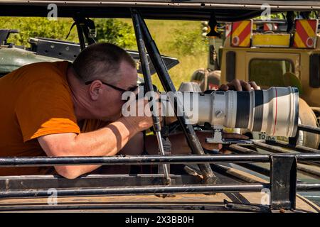 Un touriste photographie un animal sauvage lors d'un safari au Kenya Un homme avec un appareil photo dans une voiture de safari à toit ouvert voyage en Afrique. Masai Mara Na Banque D'Images