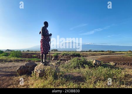 5 février 2024. Village Masai Kenya. : Homme Masai vêtu de vêtements traditionnels devant le mont Kilimandjaro dans le parc national d'Amboseli, Kenya Banque D'Images